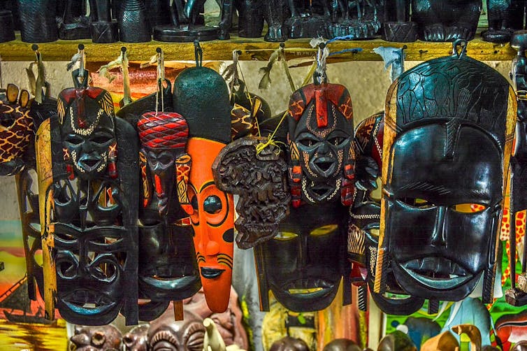 A row of wood-carved African masks, all similar.
