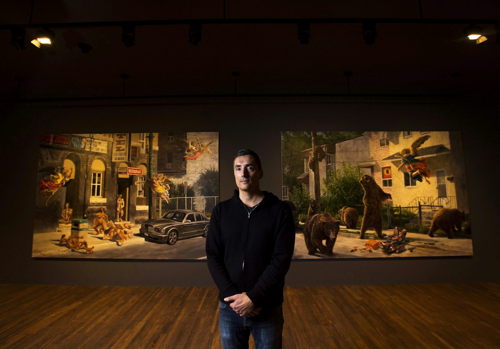 a man stands in front of two large canvasses