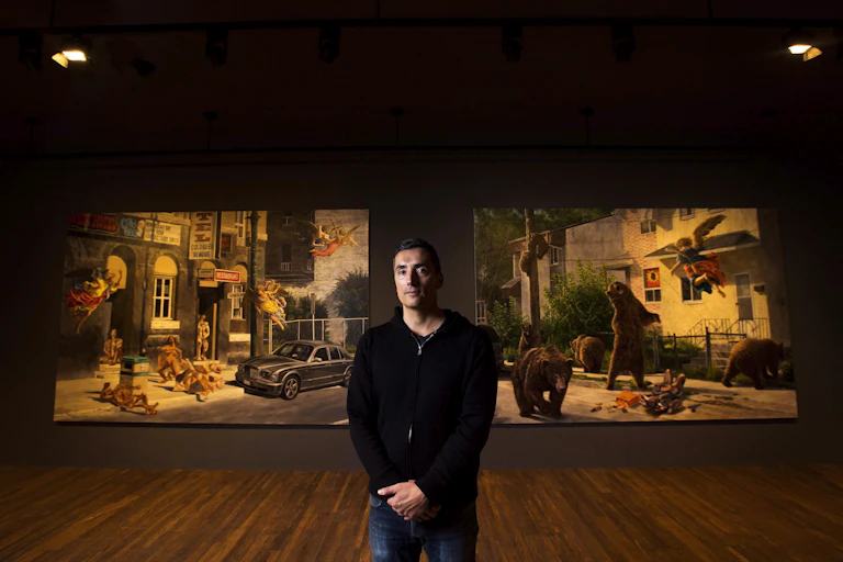 a man stands in front of two large canvasses