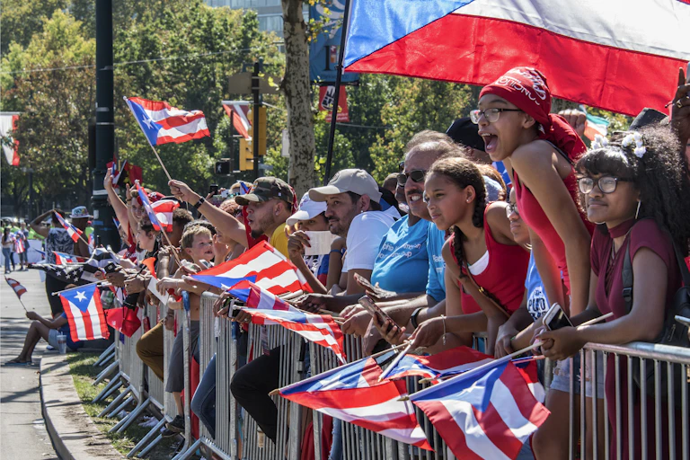 A crowd of people of varying ages hold and wave Puerto Rican flags