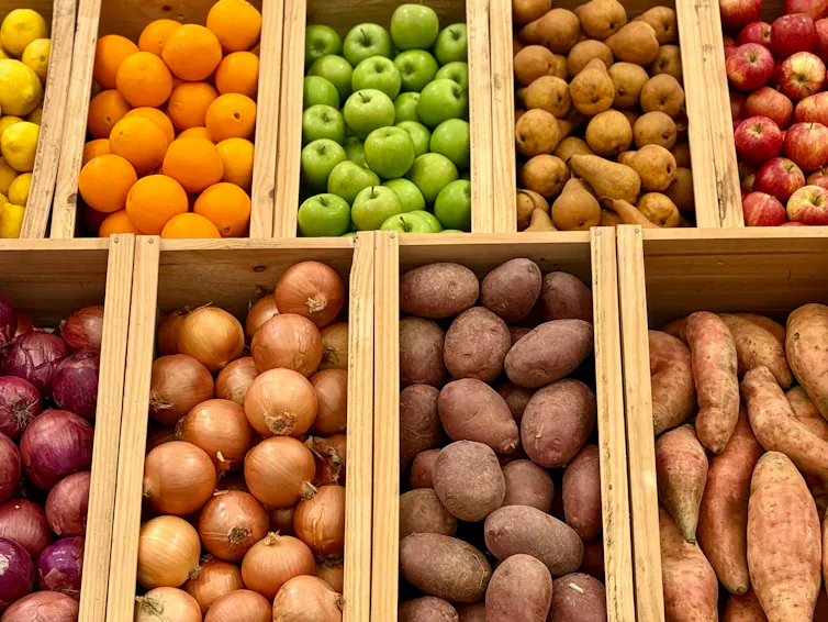 An array of fruit and vegetables, including oranges, apples, onions, potatoes