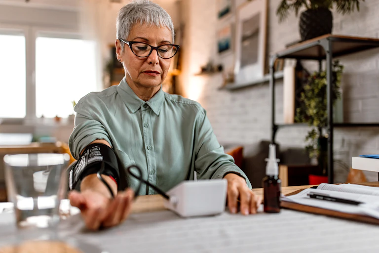 A woman using a blood pressure monitor at home.