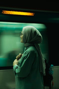 Woman in a headscarf standing by a moving train