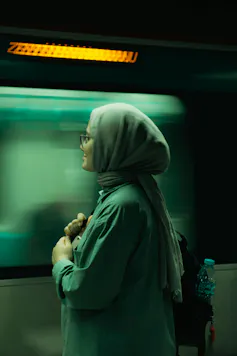 Woman in a headscarf standing by a moving train
