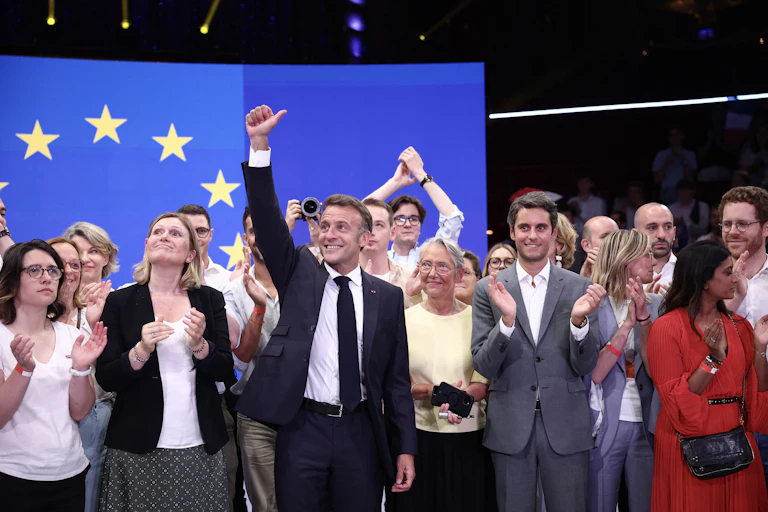 Emmanuel Macron et Gabriel Attal posent avec plusieurs figures du mouvement macroniste devant un drapeau européen.