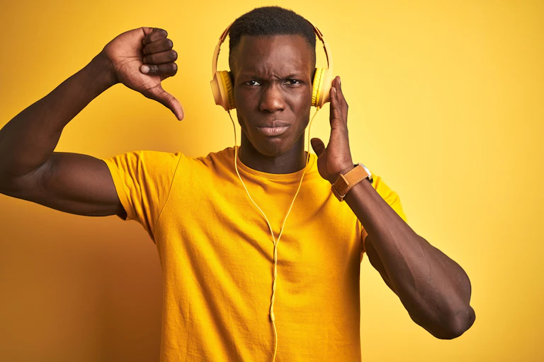 Man in yellow shirt and headphones giving a thumbs down