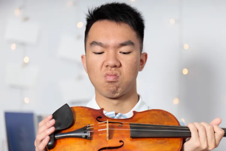 Homme renfrogné devant un violon
