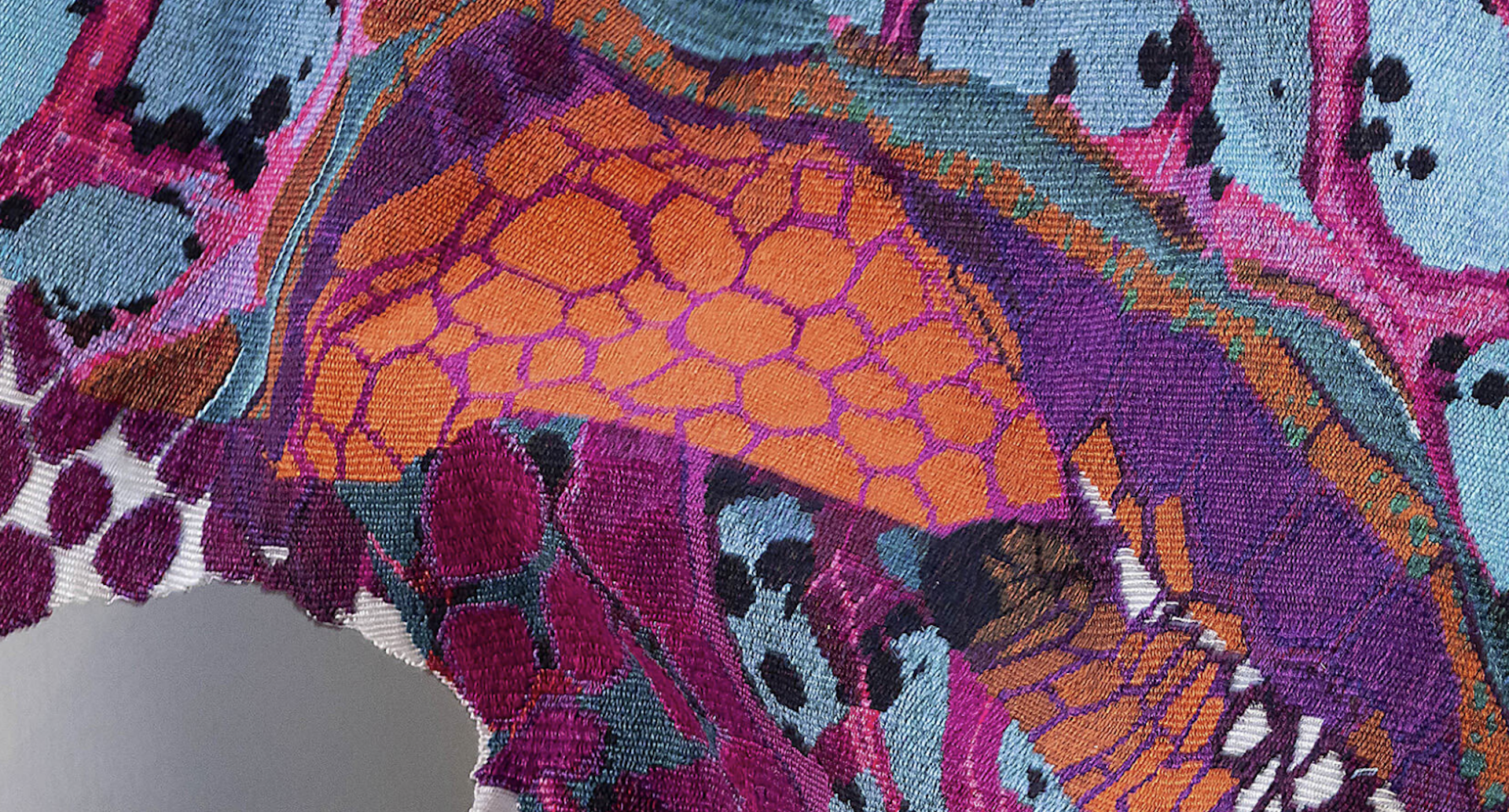 A detail from a purple and orange tapestry.