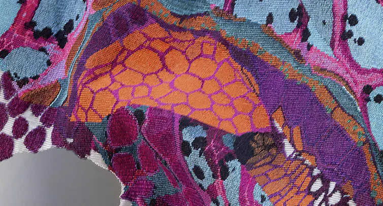 A detail from a purple and orange tapestry.