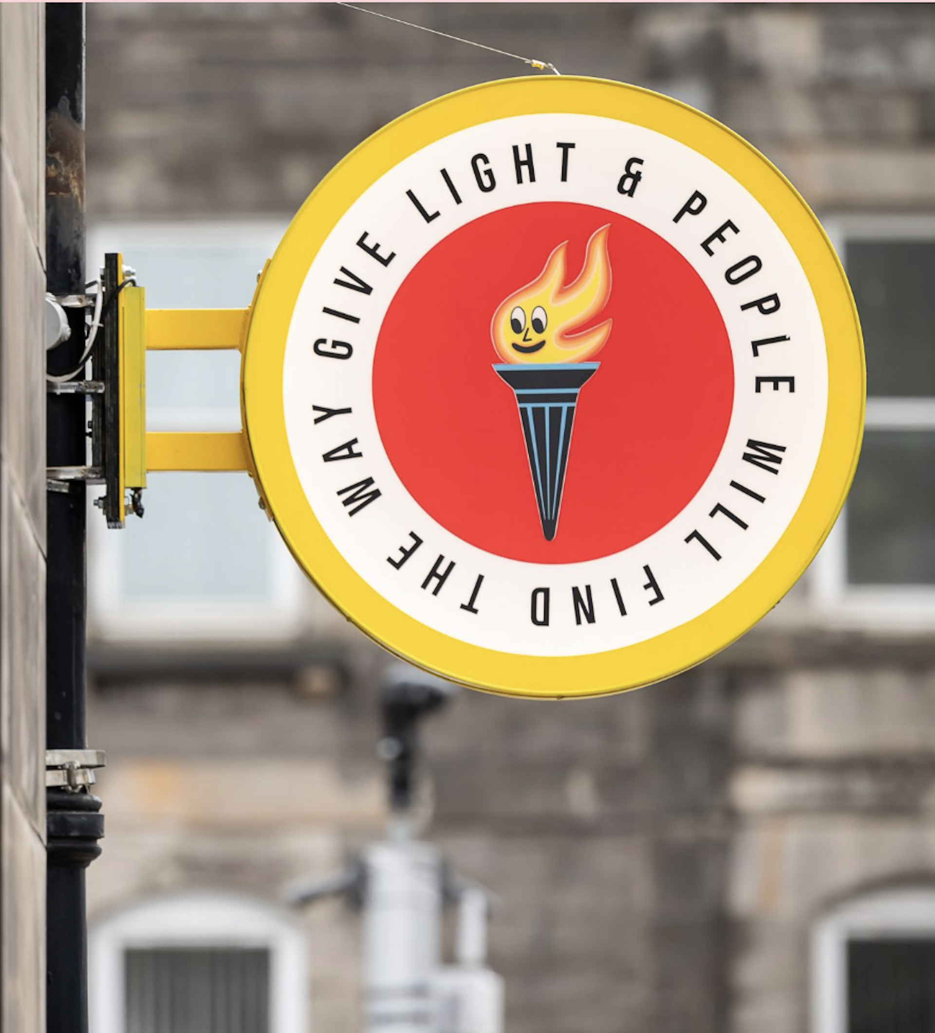 A yellow and red street sign that says Give Light And People Will Find The Way.