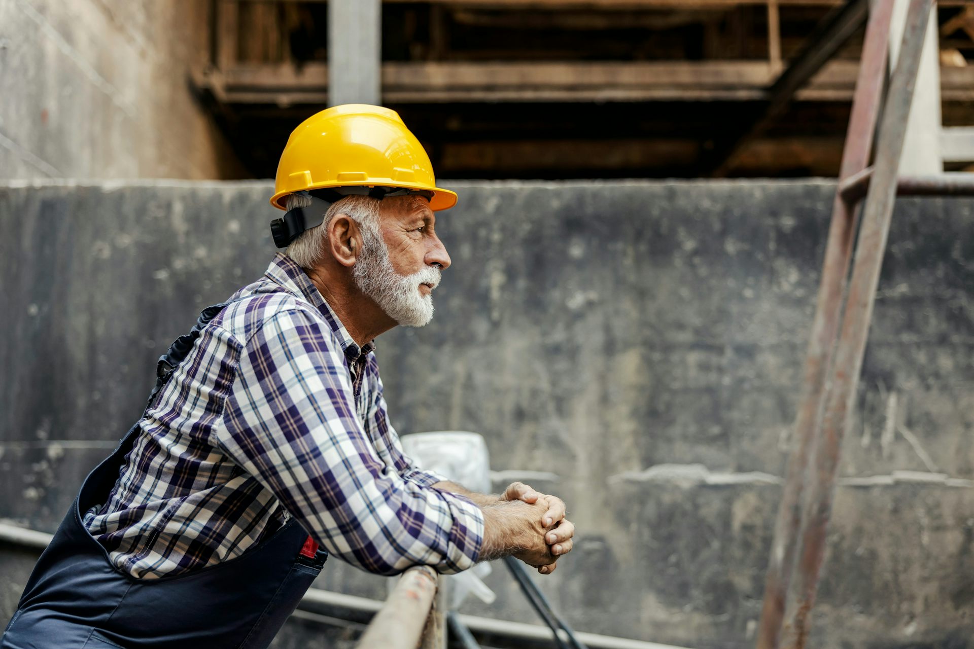 Un homme âgé en habit de construction regarde un chantier.