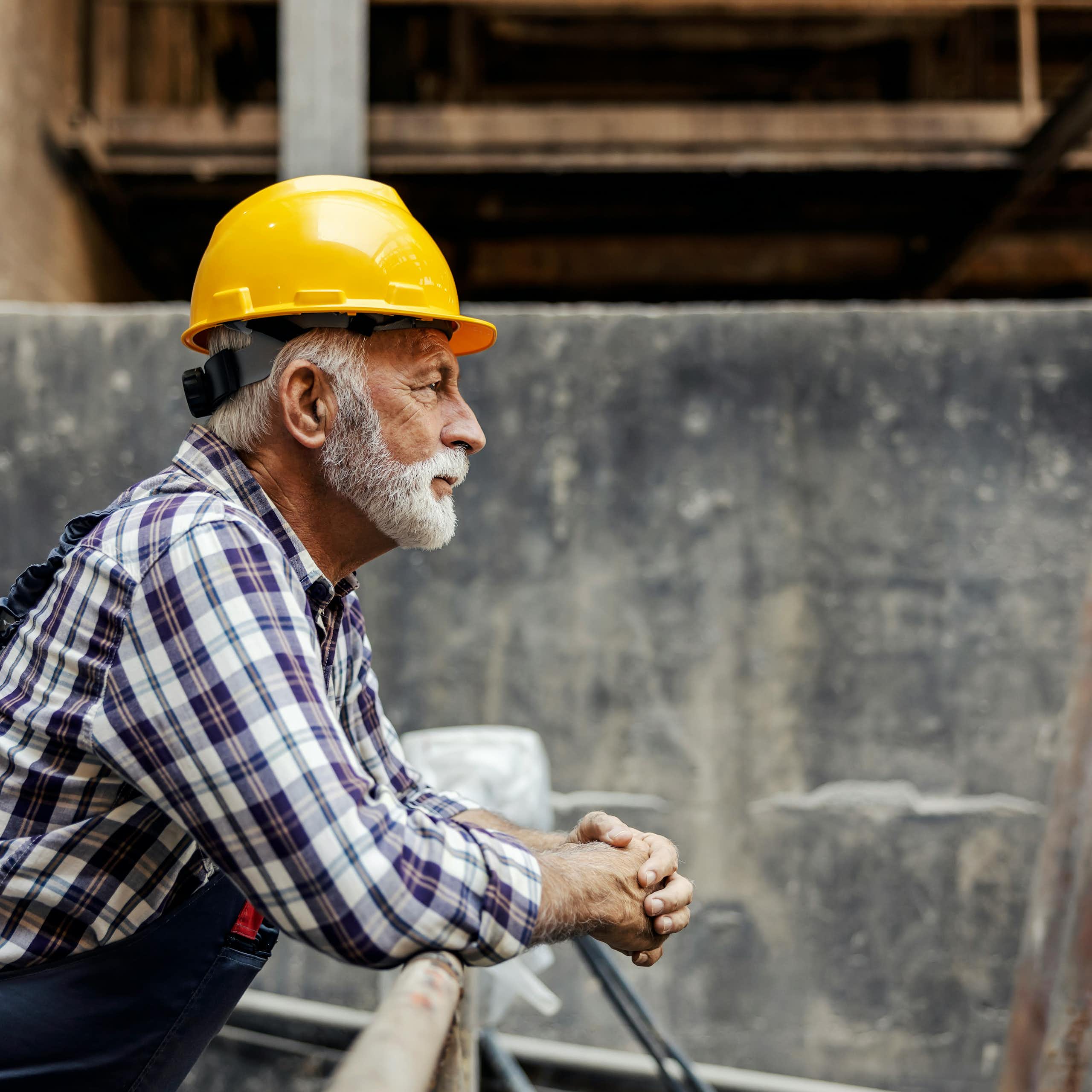 Un homme âgé en habit de construction regarde un chantier.