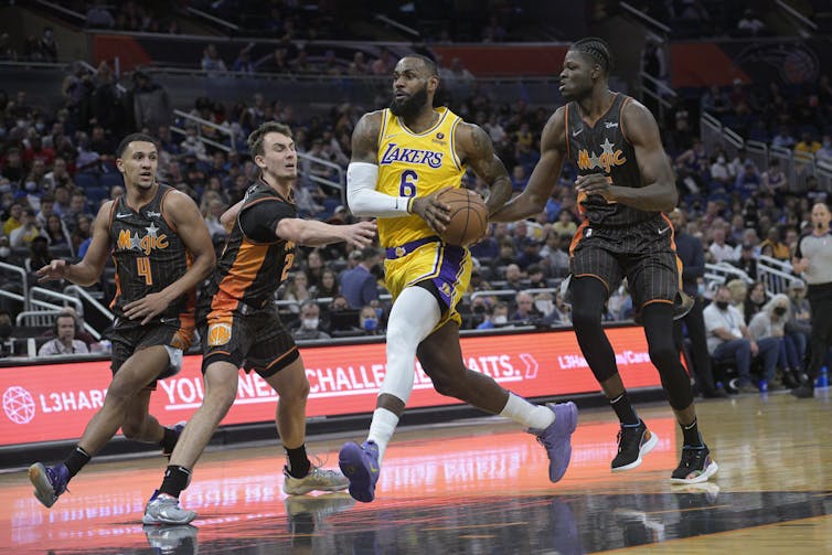Cuatro jugadores de baloncesto que corren por la cancha, centro central, LeBron James, sosteniendo baloncesto.