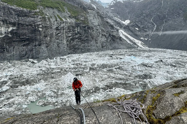 A person rappels down into a basin filled with icy water,