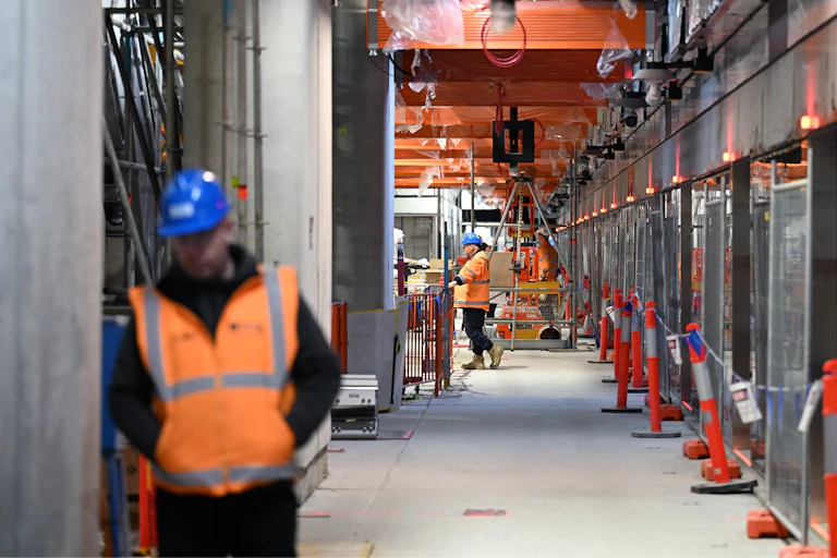 Construction workers are seen along a train platform at ANZAC Station in Melbourne.