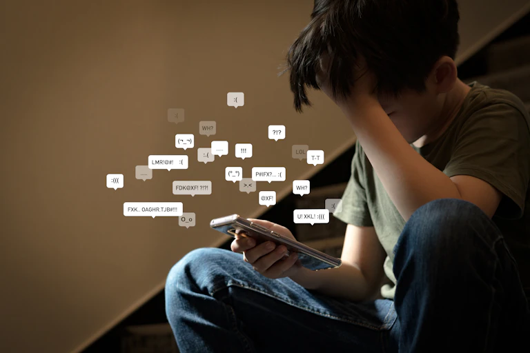 Cyberbullying - social media harassment concept. Young asian preteen, teenager boy looking at his smartphone feeling frustrated after reading bad comments.