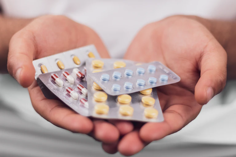 Two hands holding multiple pill blisters