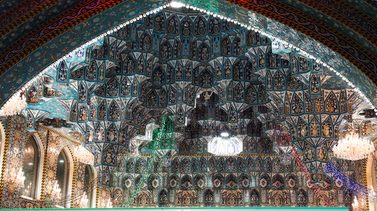 Ornately designed ceiling with mirrors set amid colorful and artistically designed tiles.