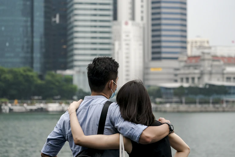 A couple embraces next to Marina Bay, Singapore.