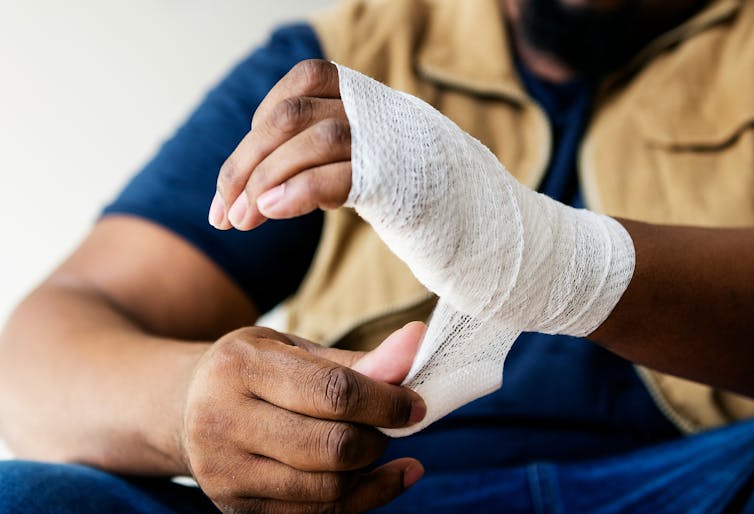 A man wraps a bandage around his hand