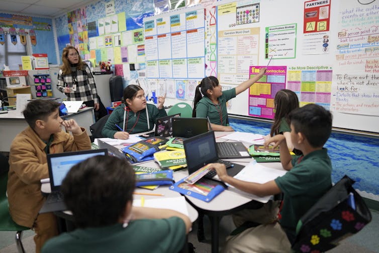 4th grade students in a California classroom presenting their work and working on computers.