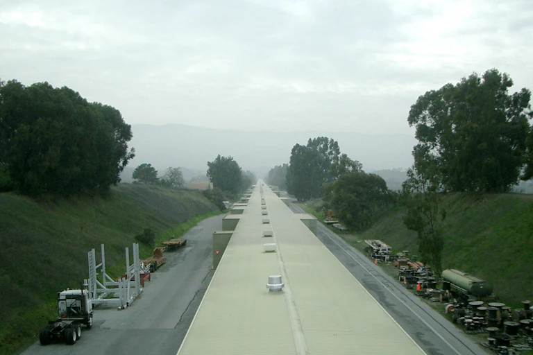 A long, thin facility shown receding into the horizon, which is cloaked in fog.