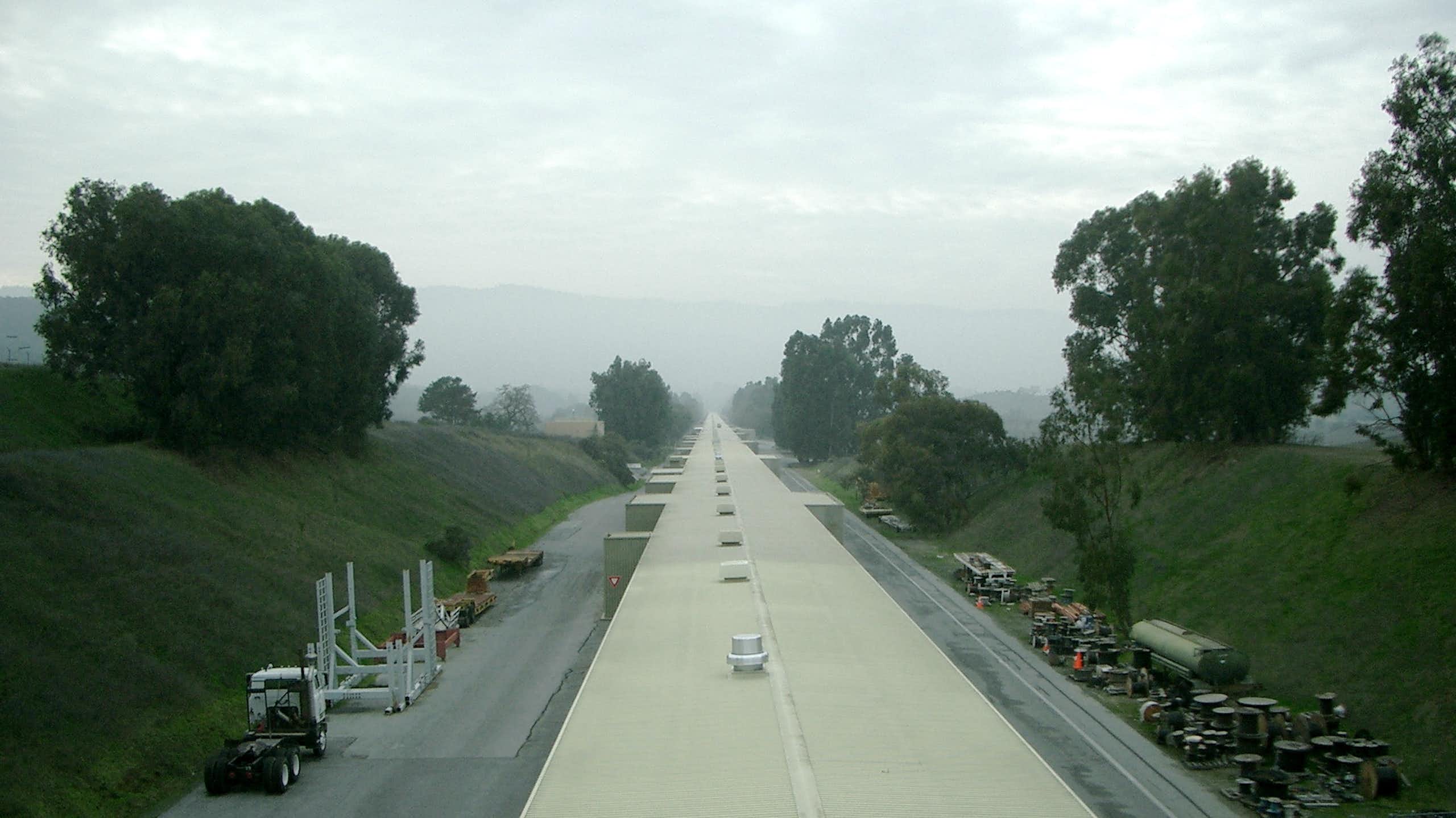 A long, thin facility shown receding into the horizon, which is cloaked in fog.