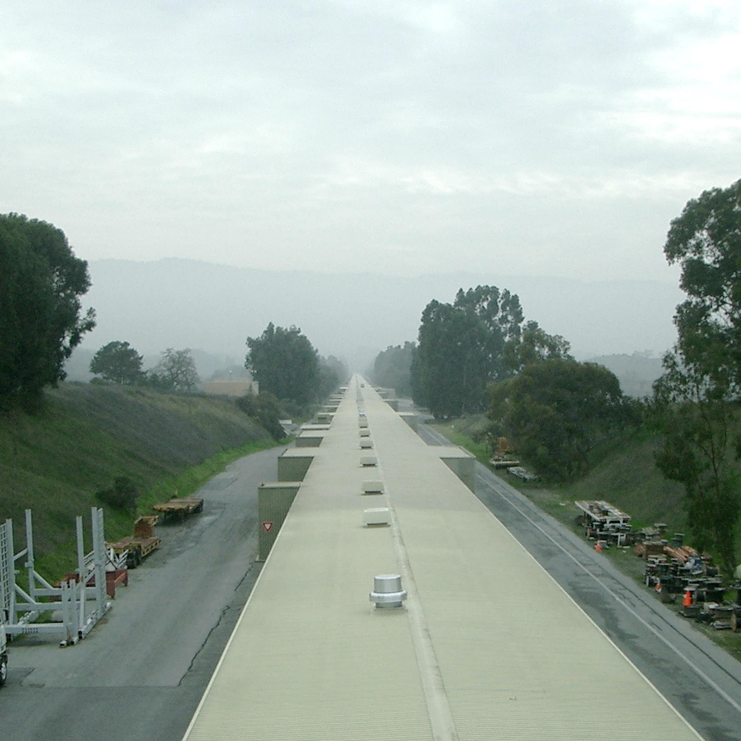 A long, thin facility shown receding into the horizon, which is cloaked in fog.