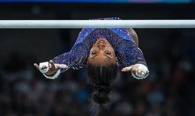 Simone Biles, the champion gymnast floats through the air with her eyes firmly riveted on a bar.