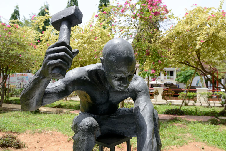 Sculpture of a man wielding a hammer, in an open park space