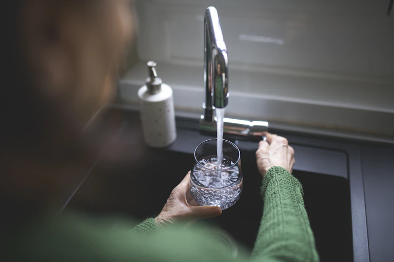 A woman filling a glass of water from the tap.