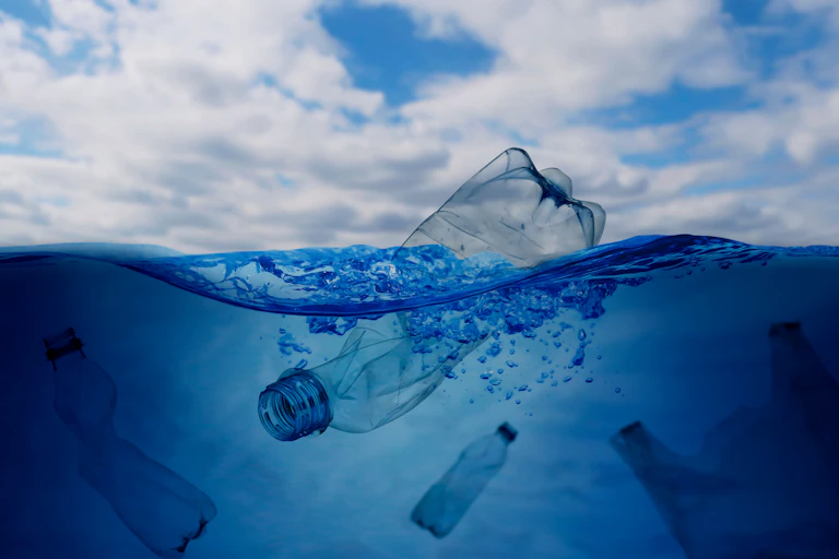 plastic bottle floating in sea, blue cloudy sky