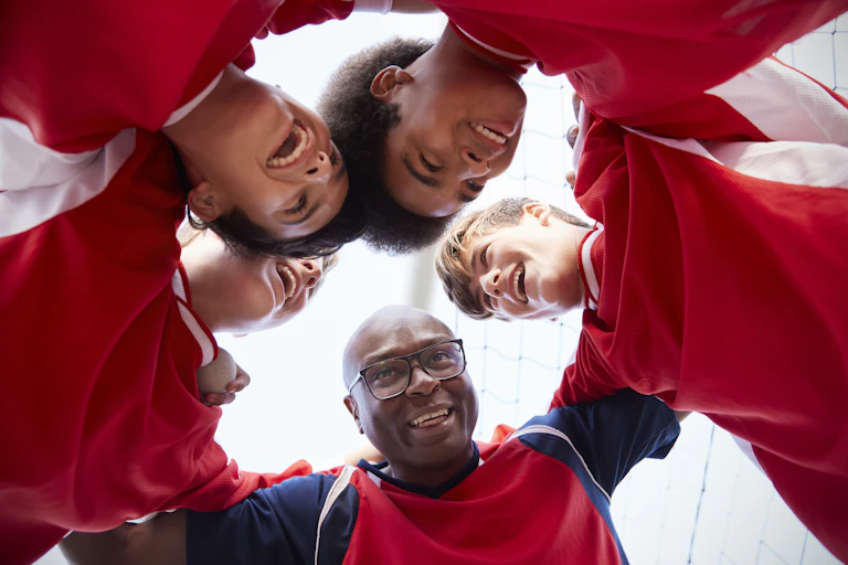 Man seen huddling with young, smiling athletes