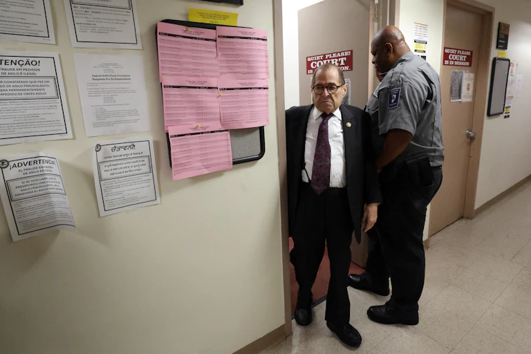 An older man with dark hair and glasses inside a government building.