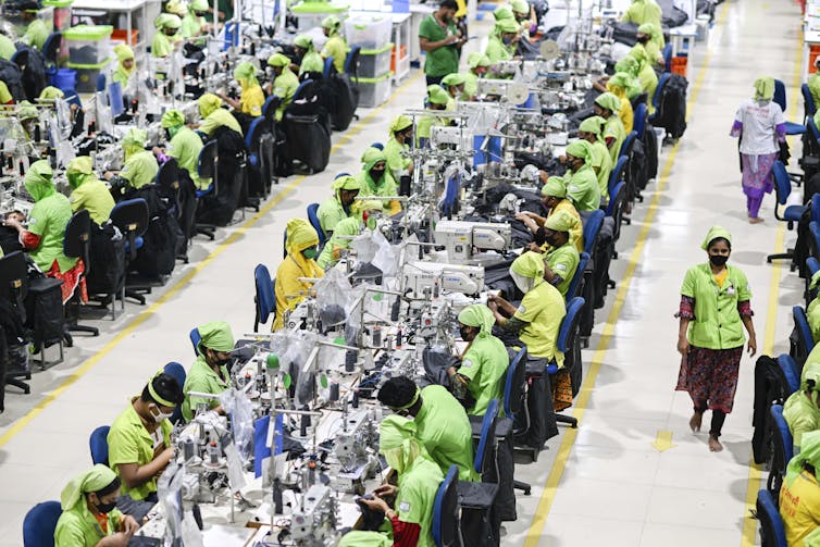 Los trabajadores exprimen la ropa en las máquinas de coser en factor
