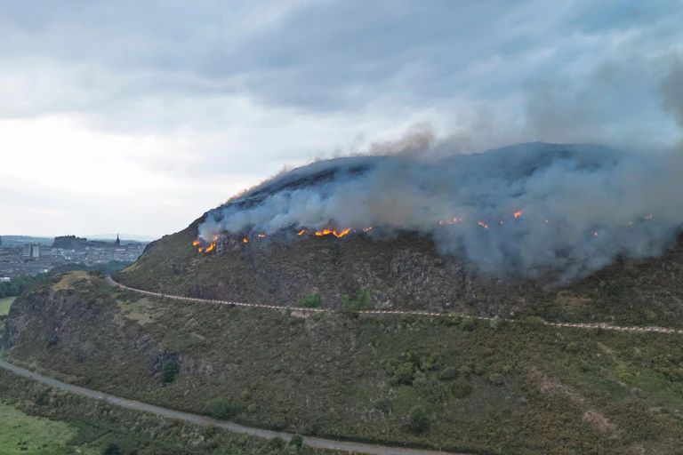 arthur's seat hillside on fire, smoke and grey sky
