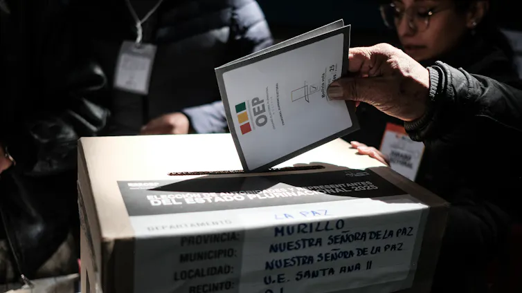 Someone puts in a ballot in a voting box.