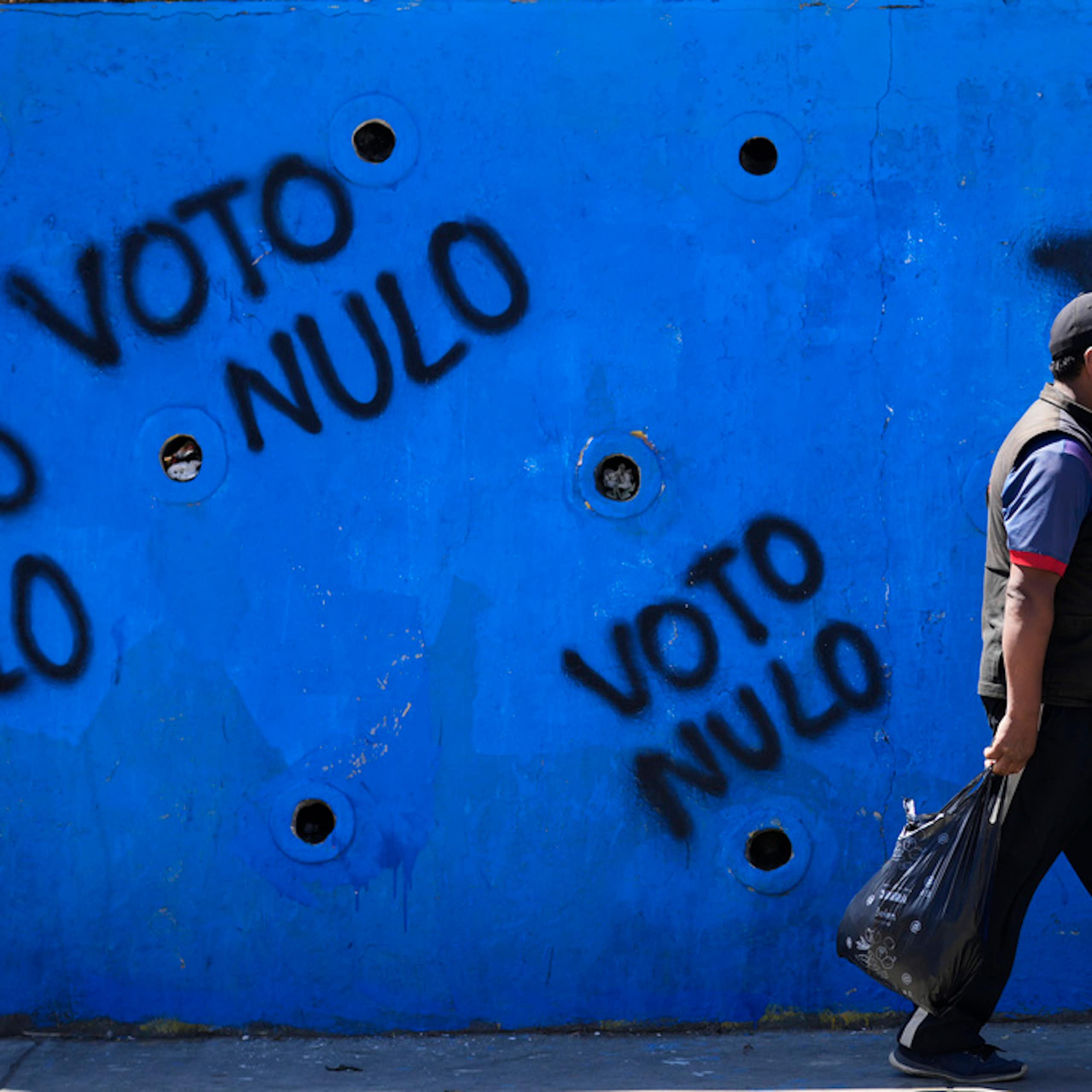 A man walks by political graffiti.