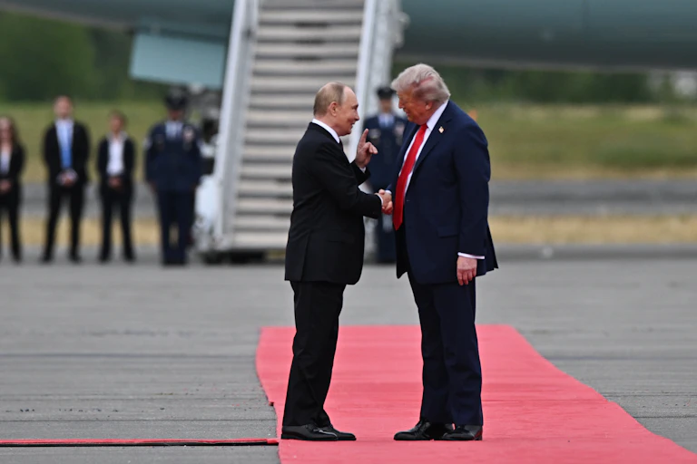 Donald Trump greets Vladimir Putin on a red carpet.