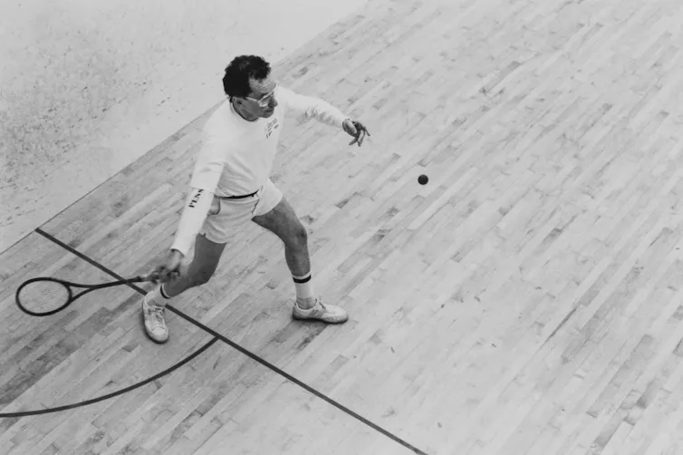 Black-and-white photo of man on court hitting ball with a racket