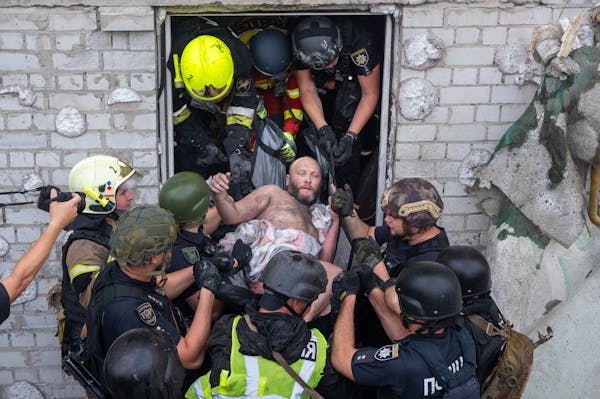 A man is carried out of a building by rescue workers.