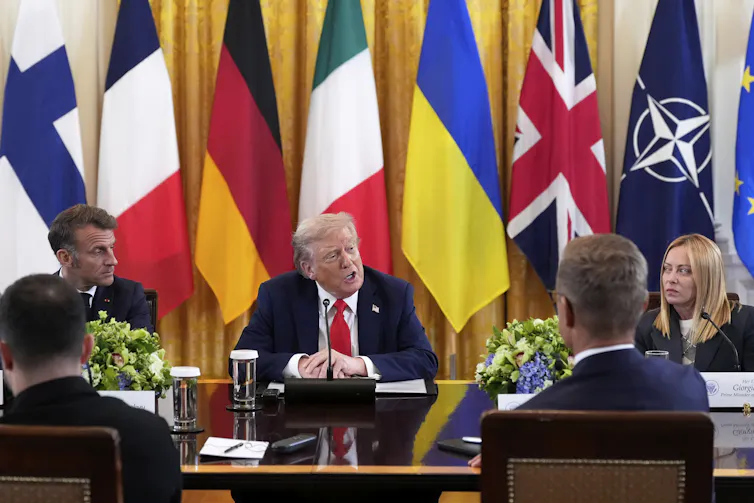 Plusieurs dirigeants écoutent Donald Trump, autour d’une table, avec plusieurs drapeaux en arrière-plan