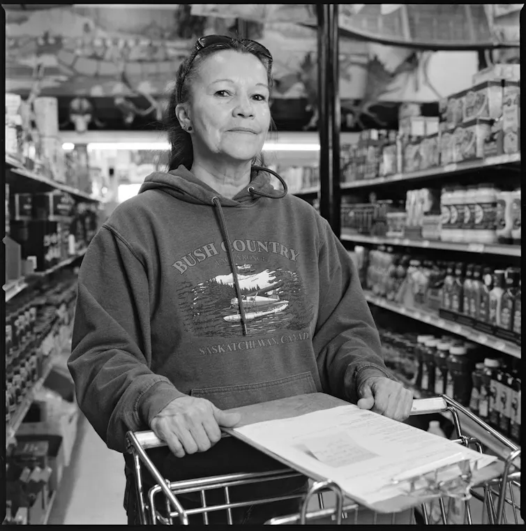 a black and white photo of a woman standing in a supermarket aisle