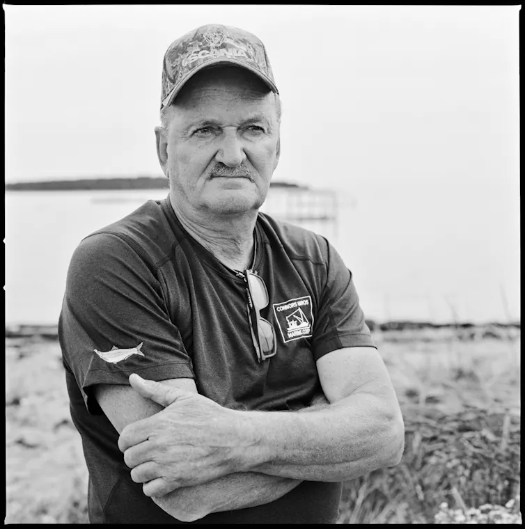 an older man with his arms folded looks into the distance