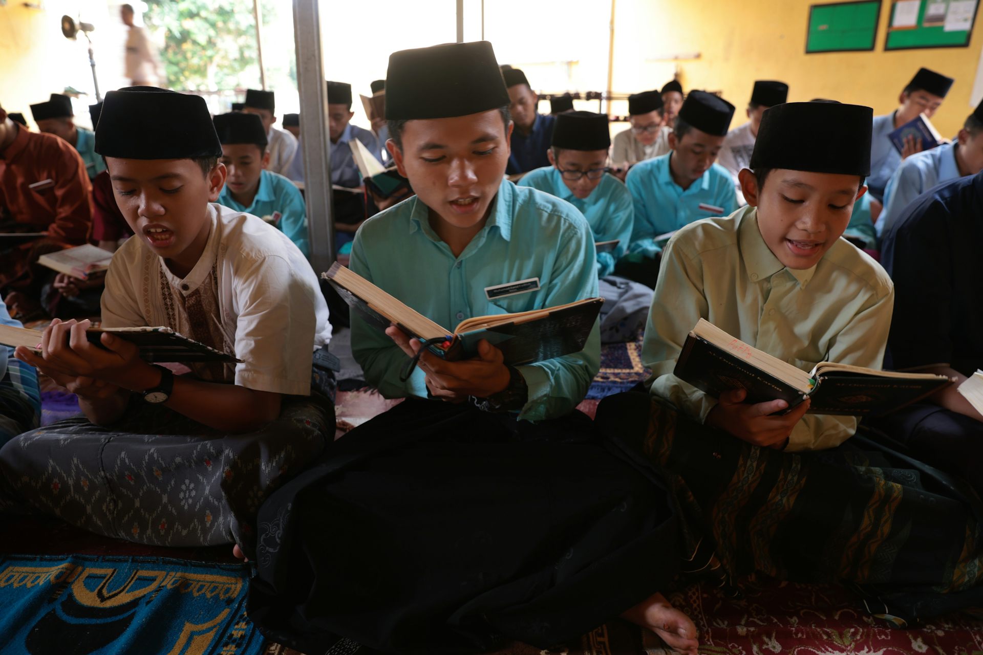 Para siswa laki-laki di sekolah Islam sedang membaca dari sebuah buku.