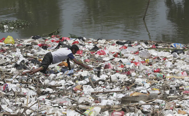 Seorang pria memilah-milah tumpukan sampah.