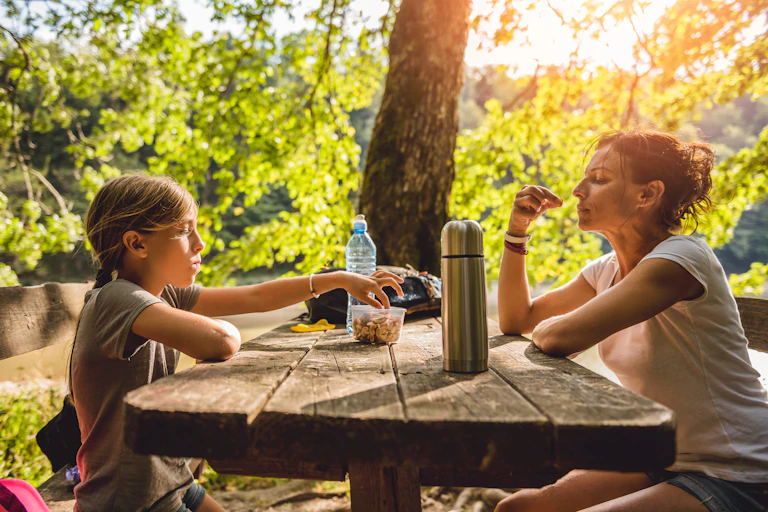 Mother and child eat nuts and drink water outdoors