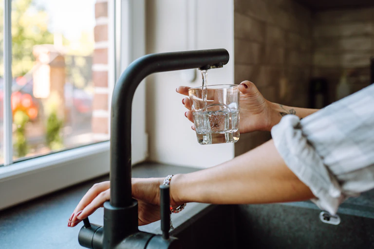 a hand filling up a glass of water from tap.
