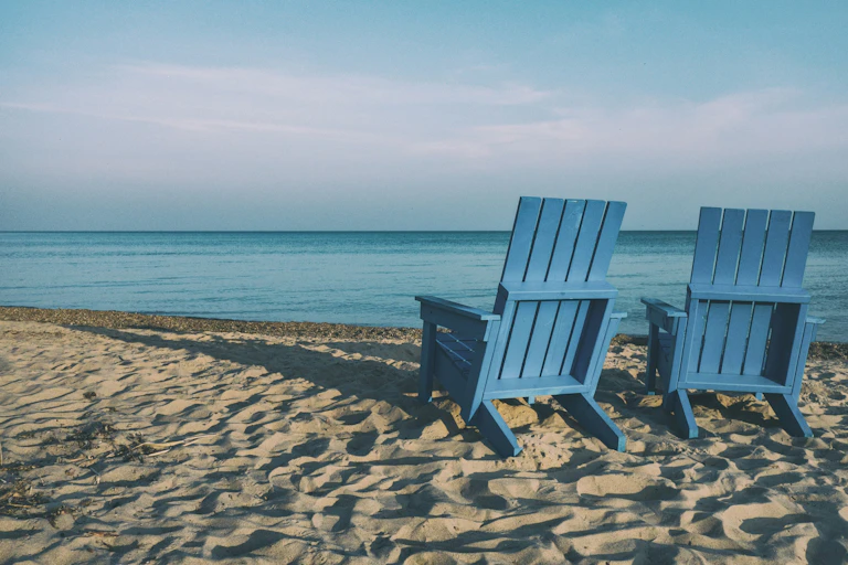 Two empty deck chairs on a beach.