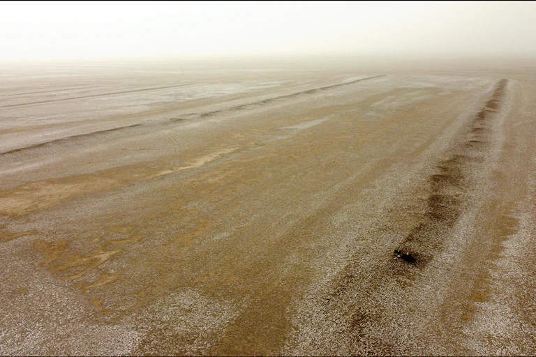 A vast brown landscape with patterns of ridges rising above it.